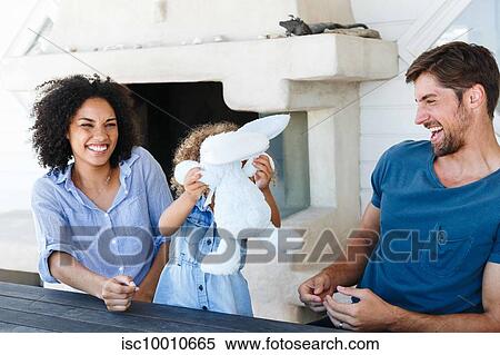 Couple talking and playing with daughter in beach house View Large Photo Image Stock Photography - Couple talking and playing with daughter in beach house. Fotosearch