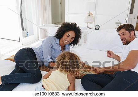 Couple talking to daughter on bed in beach house View Large Photo Image Stock Image - Couple talking to daughter on bed in beach house. Fotosearch