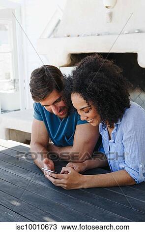 Couple using smartphone in beach house View Large Photo Image Stock Image - Couple using smartphone in beach house. Fotosearch