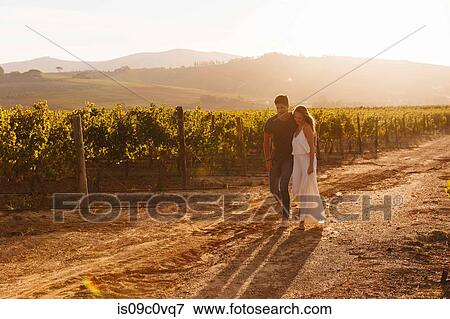 Stock Photo - Couple walking along vineyard, Cape Town, South Africa. Fotosearch