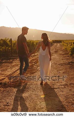 Stock Photo - Couple walking along vineyard, Cape Town, South Africa. Fotosearch