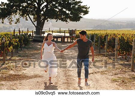 Stock Photography - Couple walking along vineyard, Cape Town, South Africa. Fotosearch