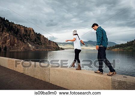 Stock Image - Couple walking along wall beside Dillon Reservoir, Silverthorne, Colorado, USA. Fotosearch
