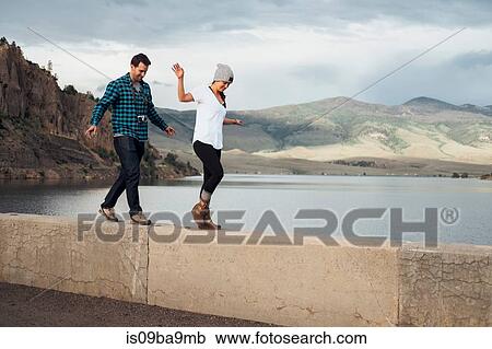 Stock Image - Couple walking along wall beside Dillon Reservoir, Silverthorne, Colorado, USA. Fotosearch