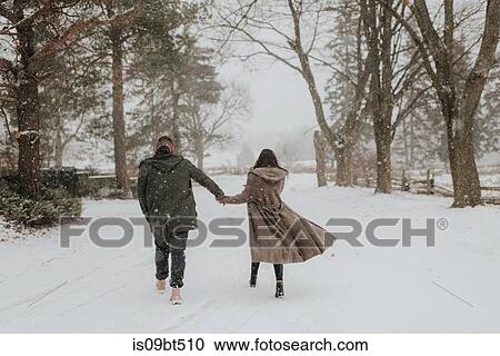Stock Image - Couple walking in snowy landscape, Georgetown, Canada. Fotosearch