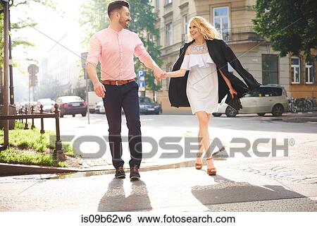 Couple walking in street holding hands View Large Photo Image Stock Photograph - Couple walking in street holding hands. Fotosearch