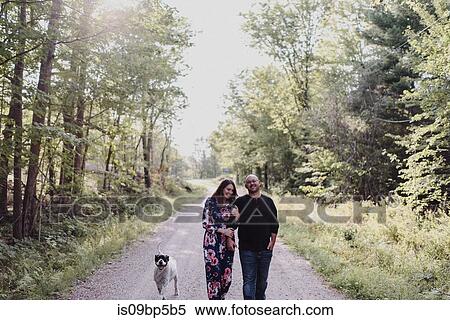 Couple walking with dog on countryside road View Large Photo Image Stock Photography - Couple walking with dog on countryside road. Fotosearch