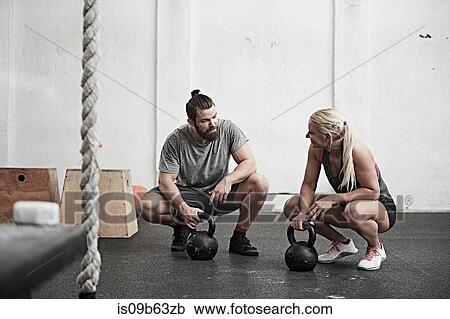 Couple with kettlebells in cross training gym View Large Photo Image Stock Image - Couple with kettlebells in cross training gym. Fotosearch