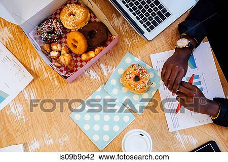Cropped overhead view of cake box of doughnuts on womans desk View Large Photo Image Stock Image - Cropped overhead view of cake box of doughnuts on womans desk. Fotosearch