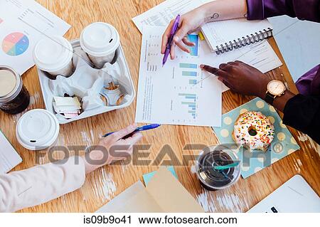 Stock Image - Cropped overhead view of doughnuts and coffees on desk. Fotosearch