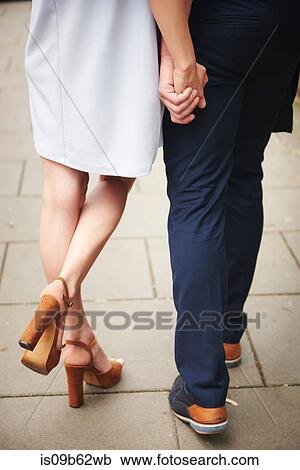 Cropped rear view of couple holding hands View Large Photo Image Stock Image - Cropped rear view of couple holding hands. Fotosearch