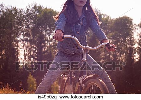 Stock Image - Cropped rural shot of teenage girl freewheeling on bicycle. Fotosearch