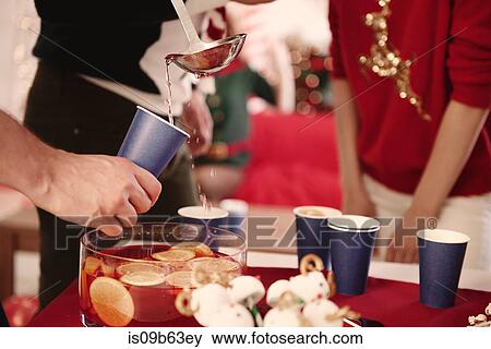 Cropped shot of young man serving punch to friends at christmas party View Large Photo Image Stock Photo - Cropped shot of young man serving punch to friends at christmas party. Fotosearch
