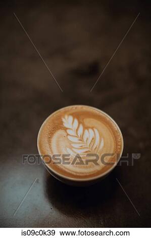 Cup of latte with leaf pattern on cafe counter, overhead view View Large Photo Image Stock Photo - Cup of latte with leaf pattern on cafe counter, overhead view. Fotosearch