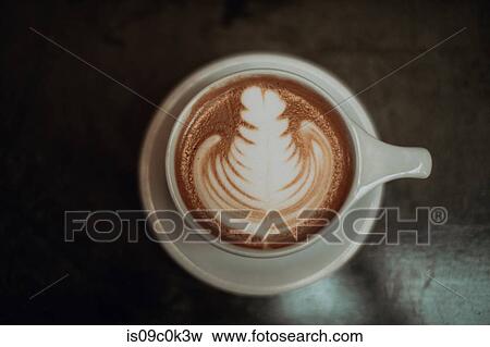 Cup of mocha topped with pattern on cafe table, low key overhead view View Large Photo Image Stock Photo - Cup of mocha topped with pattern on cafe table, low key overhead view. Fotosearch