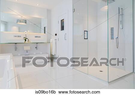 Detail of white rectangular bathtub, wall mirror, glass shower stall and sauna room door in en suite with ceramic tile flooring, upstairs inside luxury residential home View Large Photo Image Stock Image - Detail of white rectangular bathtub, wall mirror, glass shower stall and sauna room door in en suite with ceramic tile flooring, upstairs inside luxury residential home. Fotosearch
