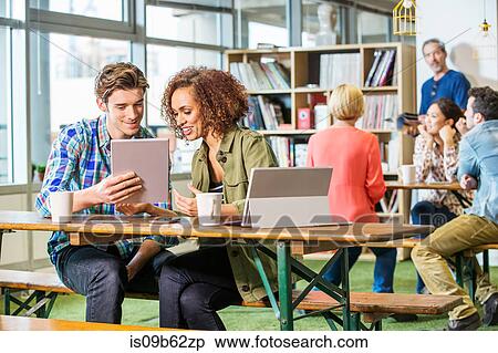 Digital designers at office table looking at digital tablet View Large Photo Image Stock Photography - Digital designers at office table looking at digital tablet. Fotosearch