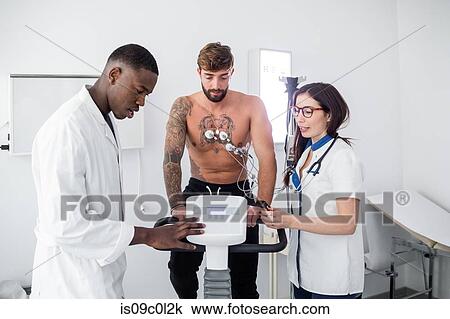 Doctor and nurse performing ECG test on patient in consultation room View Large Photo Image Stock Image - Doctor and nurse performing ECG test on patient in consultation room. Fotosearch