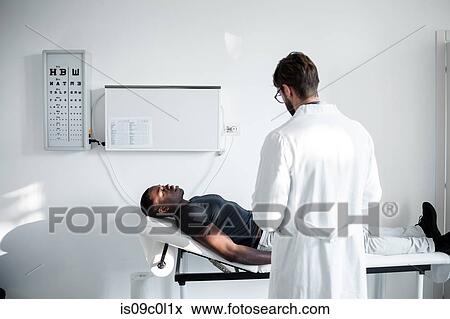 Stock Photo - Doctor examining patient in consultation room. Fotosearch