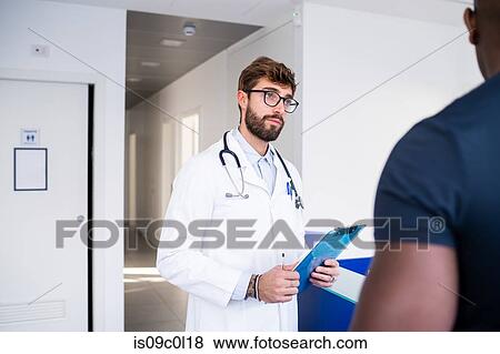 Doctor speaking with patient at hospital reception View Large Photo Image Stock Photo - Doctor speaking with patient at hospital reception. Fotosearch