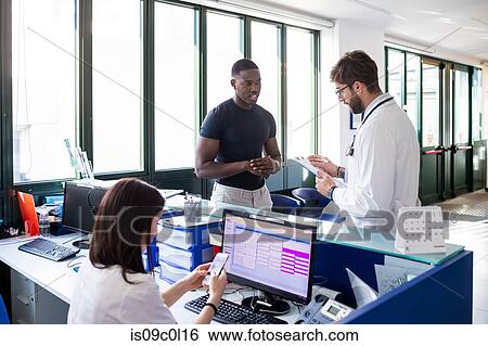 Doctor speaking with patient at hospital reception View Large Photo Image Stock Photograph - Doctor speaking with patient at hospital reception. Fotosearch