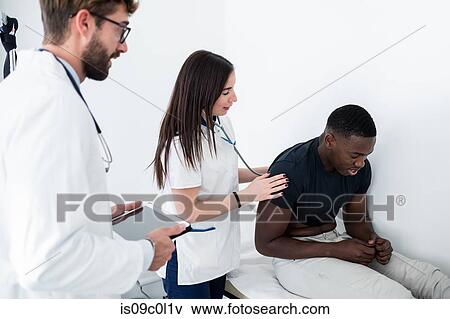 Stock Photo - Doctor watching nurse examine patient in consultation room. Fotosearch