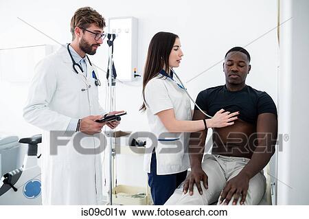Doctor watching nurse examine patient in consultation room View Large Photo Image Stock Photo - Doctor watching nurse examine patient in consultation room. Fotosearch