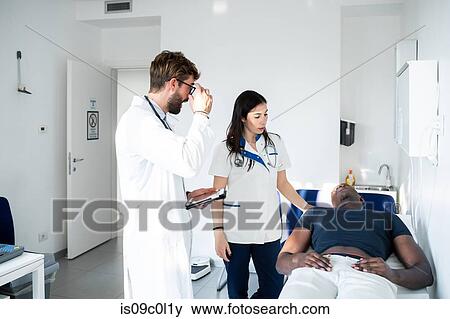 Doctor watching nurse examine patient in consultation room View Large Photo Image Stock Photo - Doctor watching nurse examine patient in consultation room. Fotosearch