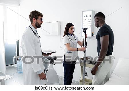 Stock Photograph - Doctor watching nurse examine patient in consultation room. Fotosearch