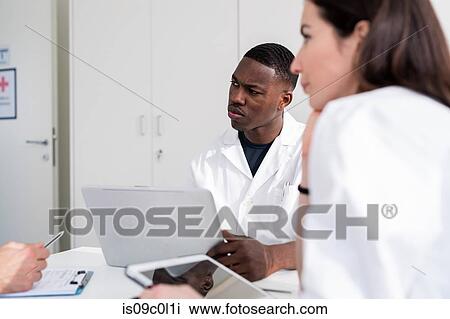 Stock Image - Doctors having discussion in meeting room. Fotosearch