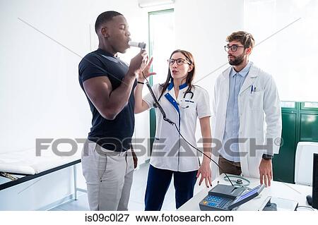 Doctors watching patient blow into breathalyser machine in hospital View Large Photo Image Stock Photo - Doctors watching patient blow into breathalyser machine in hospital. Fotosearch