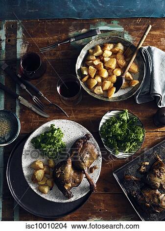 Picture - Duck confit, roast potatoes and broccoli rabe. Fotosearch