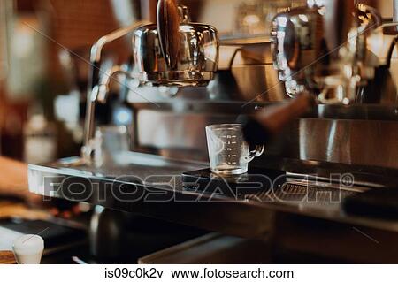 Stock Photo - Empty measuring jug on coffee machine stand in cafe. Fotosearch