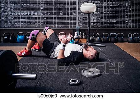 Exhausted young man taking break in gym View Large Photo Image Stock Image - Exhausted young man taking break in gym. Fotosearch