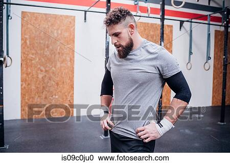 Stock Image - Exhausted young man taking break in gym. Fotosearch