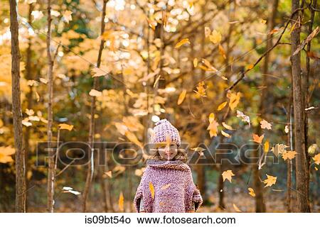 Falling autumn leaves in front of little girl in forest View Large Photo Image Picture - Falling autumn leaves in front of little girl in forest. Fotosearch