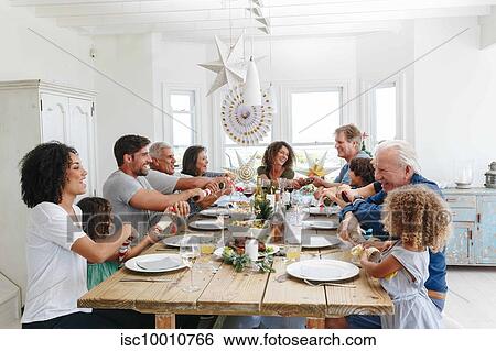 Family popping Christmas crackers together at dining table View Large Photo Image Stock Photograph - Family popping Christmas crackers together at dining table. Fotosearch