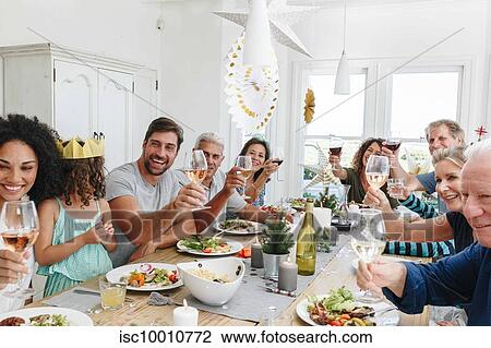 Stock Image - Family toasting wine at dining table in home party. Fotosearch