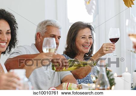 Stock Image - Family toasting wine at home party. Fotosearch