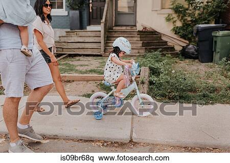 Family walking with daughter on tricycle View Large Photo Image Stock Photography - Family walking with daughter on tricycle. Fotosearch