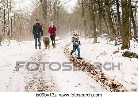 Stock Photo - Family with pet dog on walk in snow landscape. Fotosearch