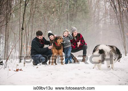 Stock Photograph - Family with pet dogs on walk in snow landscape. Fotosearch