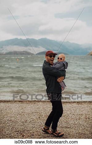 Stock Photo - Father and baby on beach, Queenstown, Canterbury, New Zealand. Fotosearch