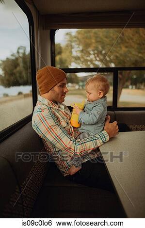 Stock Photograph - Father and baby relaxing in motorhome, Wanaka, Taranaki, New Zealand. Fotosearch