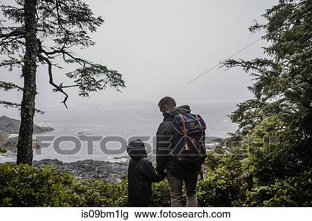 Stock Image - Father and child looking out to sea, Tofino, Canada. Fotosearch