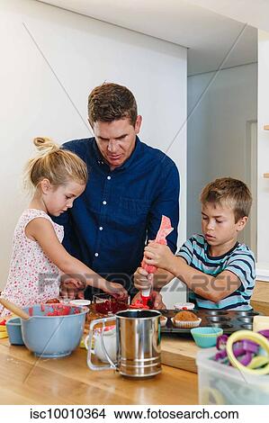 Father and children decorating cupcakes with frosting in kitchen View Large Photo Image Picture - Father and children decorating cupcakes with frosting in kitchen. Fotosearch
