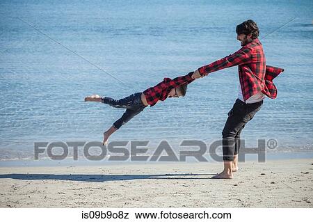 Father and son on beach, father holding son's hands, swinging him around View Large Photo Image Stock Photo - Father and son on beach, father holding son's hands, swinging him around. Fotosearch