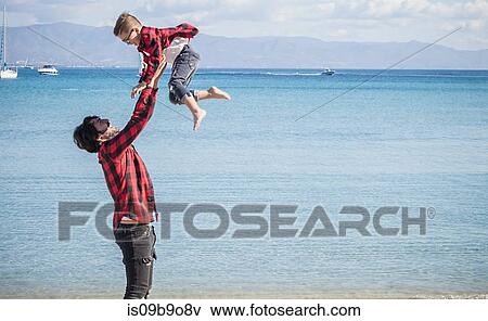 Father and son on beach, father lifting son in air View Large Photo Image Stock Photo - Father and son on beach, father lifting son in air. Fotosearch