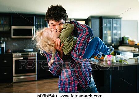 Stock Photograph - Father and son playing in kitchen. Fotosearch