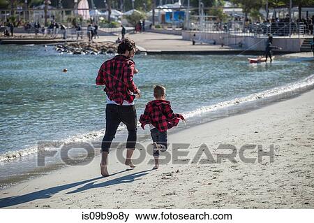 Father and son running along beach, rear view View Large Photo Image Stock Photo - Father and son running along beach, rear view. Fotosearch